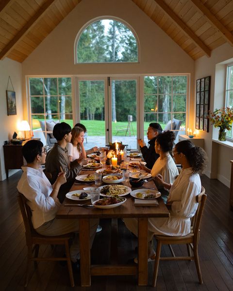 Zehn Freunde beim Abendessen an einem langen Tisch in einem Ferienhaus